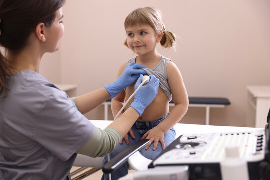 Sonographer conducting ultrasound examination of little girl's heart in clinic - Powered by Adobe