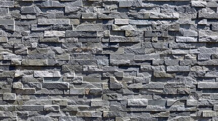 External wall covering made of  bricks of different shades of gray and white rock. Stone panels, background and texture.