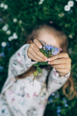 A girl holding the germander speedwellflower (Veronica chamaedrys) in her outstretched arms. Spring theme. Selective focus. Bokeh. Blurred background. 