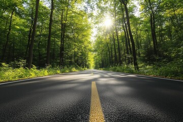 Obraz premium Paved road with yellow dividing line extending through a vibrant green forest, illuminated by bright sunlight filtering through the trees, creating a picturesque scene of tranquil nature and travel
