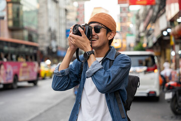 Young Asian traveling backpacker in Khaosan Road outdoor market in Bangkok Thailand. Happy tourist walking in the downtown street traditional market