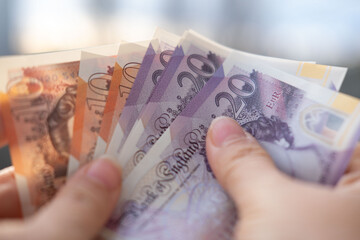 Close-up female hands counting uk pounds bills, paper money on blurred background, British GBP...
