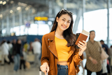 Happy young asian woman traveler using smartphone and holding boarding pass while standing at the...