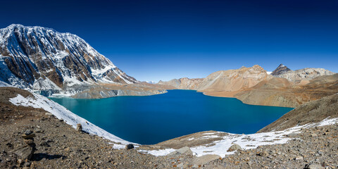 Tilicho lake with still and bright blue water in calm weather in autumn sunny day. A sacred to Buddhists and Hindus lake in Himalaya mountain in Annapurna area, Nepal.