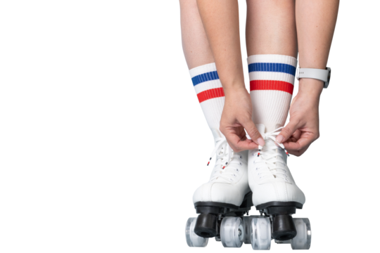 Female lacing up white roller skates with striped socks.