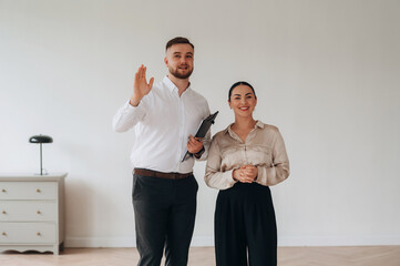 Realtor is showing the interior. Man and woman are in the modern new room, conception of business