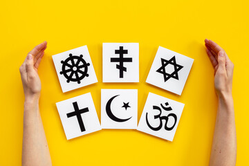 World religious concept. Hands holding Christianity cross, Islam crescent, Buddhism dharma wheel, Hinduism aum, Judaism David star symbols, top view