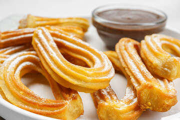 Traditional spanish dessert churros, fried dough pastry dusted with powdered sugar and chocolate sause macro, close up, on white background. Street food, sweet snack, homemade dessert