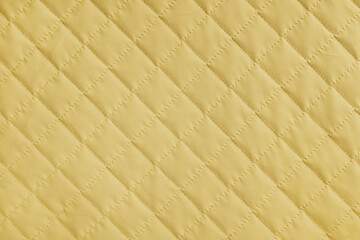 Obraz premium Checkered, diamond stitching pattern, yellow quilted fabric background. Blanket or puffer jacket, stitch rhombus texture close up, macro. Wallpaper, backdrop.