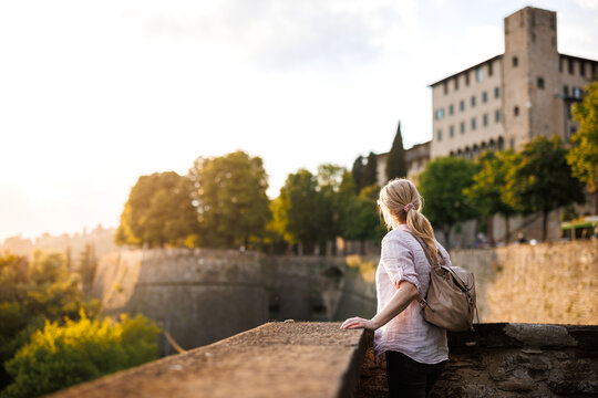 Woman tourist enjoying sunset view from city Venetian walls of Bergamo, Italy during solo travel vacation in Europe