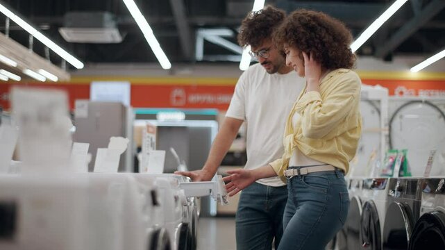 Couple choosing washing machine in electronics store in slow motion