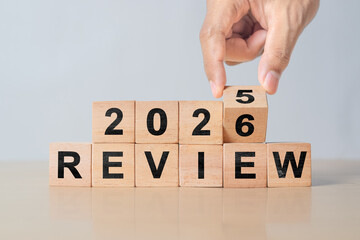 2026 review new year. hand turns wooden cube and changes number Review 2025 to Review 2026. Business, 2026 review new year concept. gray background