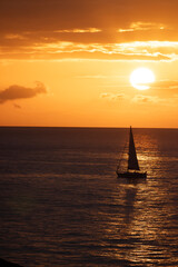 Pequeño velero cruzando a través del reflejo del sol al atardecer
