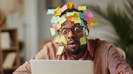 Overwhelmed african american professional wearing sticky notes, staring intently at laptop screen within chaotic workspace, displaying extreme workplace stress and exhaustion - Powered by Adobe