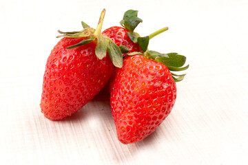 Heap of fresh strawberries in bowl on white wooden background. Top view point.
