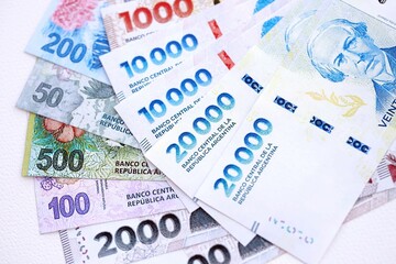 Argentine pesos money bills in big amount lies on white table close up