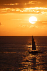 Pequeño velero cruzando a través del reflejo del sol al atardecer