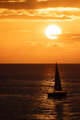 Pequeño velero cruzando a través del reflejo del sol al atardecer