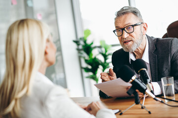 Mature businessman conducting an interview with a female professional in an office setting...