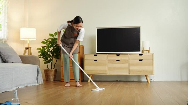 Young housewife is cleaning, wiping and mopping the floor. Clean mopping concept.