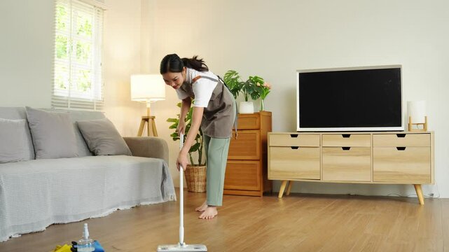 Young housewife is cleaning, wiping and mopping the floor. Clean mopping concept.