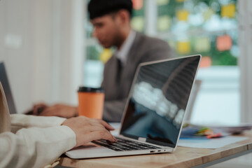 Cheerful Asian businessman and woman looking at laptop screen, analyzing project success in office.