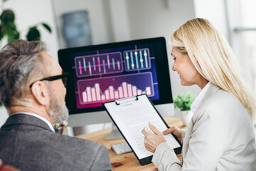 Business professionals collaborating in a modern office, analyzing data on a computer and...