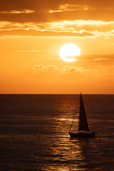 Pequeño velero cruzando a través del reflejo del sol al atardecer