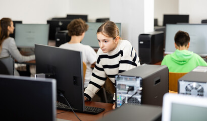 Portrait of female schoolgirl at computers in university computer class