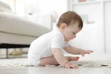 Naklejka premium Cute little baby sitting on floor at home