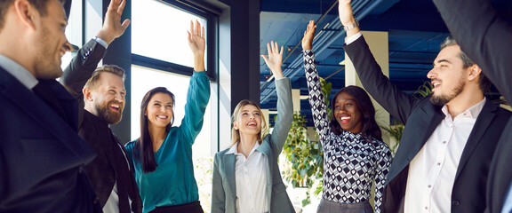 Business team, company standing in a circle, raising hands together in a joyful celebration of...
