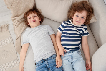 Cute little brothers laying together on sofa, above view