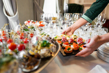 Elegant food presentation featuring assorted appetizers on a tray, including meats, cheeses, and vegetables, set on a table with empty wine glasses, ready for an event or gathering.