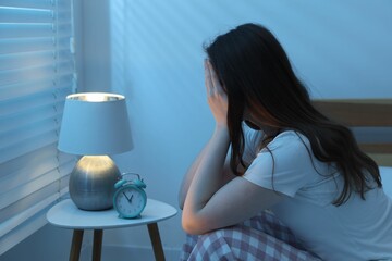 Frustrated young woman suffering from insomnia on bed indoors