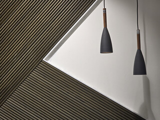 Modern pendant lights hang against textured wall featuring diagonal lines, creating stylish and contemporary atmosphere. contrast of materials adds depth and interest