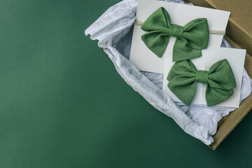 Eco-friendly packaging with two green fabric hair bows on white cards placed inside a brown kraft...