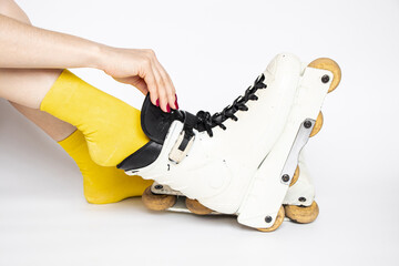 Female foot putting on reinforced aggressive roller skates on white background, preparing for...
