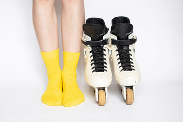 Female legs in yellow socks near white aggressive roller skates on white background, roller