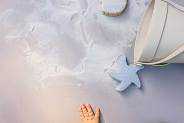 Toddler playing with pastel-colored silicone beach toys in the sand, including a bucket, scoop, starfish, dolphin, and whale shapes. Warm sunlight creates soft shadows and a peaceful summer mood