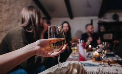 A gathering of friends enjoying conversation, food, and wine around a warmly lit table.