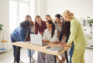 Fototapeta premium Young diverse female business people discussing job project or new startup with brainstorming sitting at the desk in office. Women working on a meeting with laptop together. Teamwork concept.