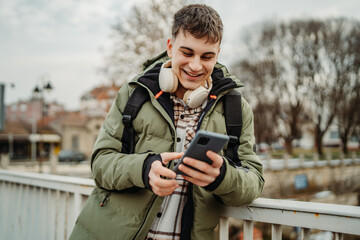 Young adult caucasian man student smile using smartphone to talk or send messages sms