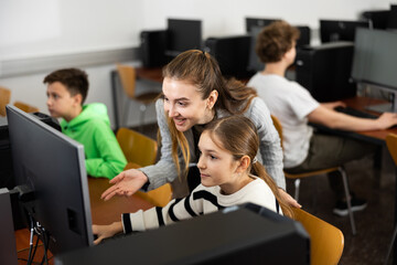 Fototapeta premium Positive woman teacher together with the girl teaches how to work on the computer