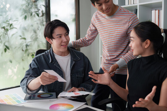 Creative Workshop and Team Dynamics. A diverse team discussing design ideas with color swatches in a modern workspace.