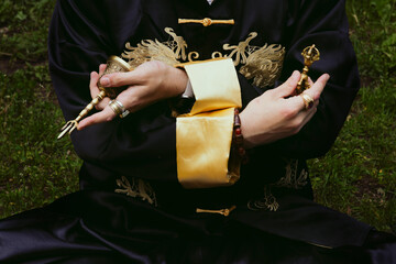 Man dressed as shaman or Wu, a Chinese sorcerer, holds metal accessories for a ceremony