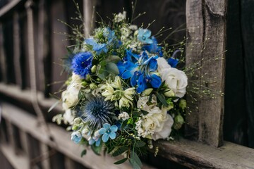 Vibrant blue and white floral bouquet on rustic fence.