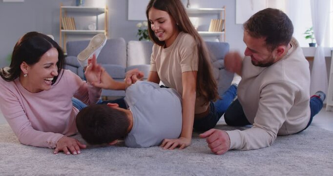 Parents and kids enjoying family leisure time together, laughing, playing, and tickling each other at home. A joyful moment of togetherness, bonding, and fun in a warm family environment.
