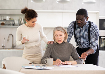 Couple man and woman discussing testament with elderly woman in kitchen at home