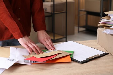 Woman putting barcodes onto envelopes at table in post office, closeup