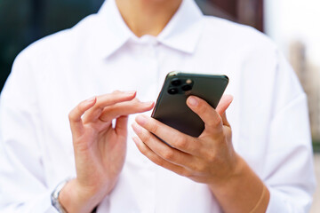 Fingers delicately tapping on a smartphone in an urban setting during a bright day, showcasing modern connectivity